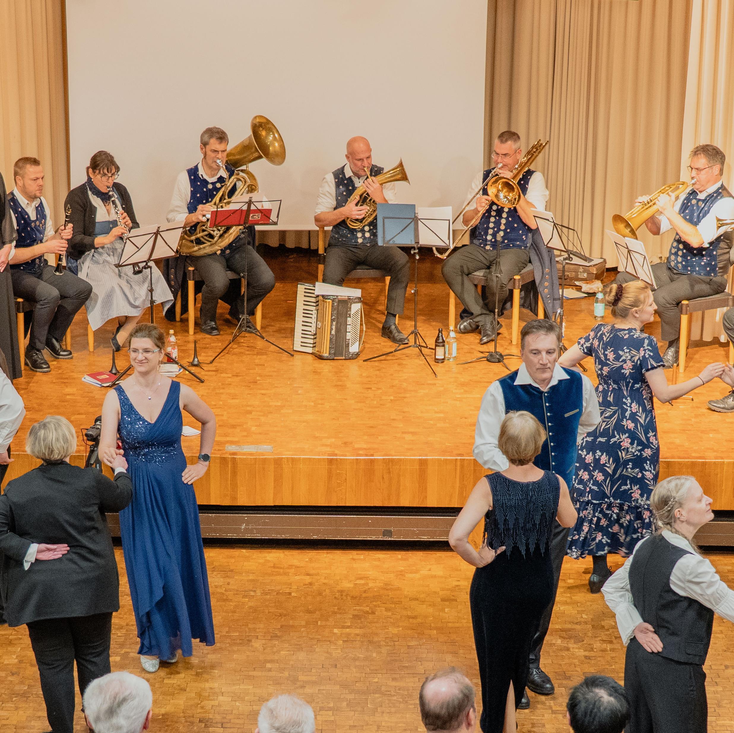 Tanzende Paare in Abendrobe vor kleinem Orchester 