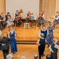 Tanzende Paare in Abendrobe vor kleinem Orchester 